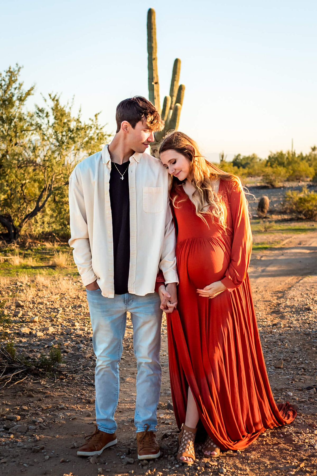 expecting parents walk side by side through Arizona desert. Photographed by Cactus & Pine Photography
