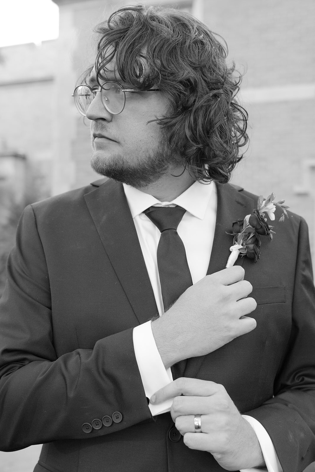 Refined black and white portrait of groom adjusting lapel before luxury San Antonio wedding reception