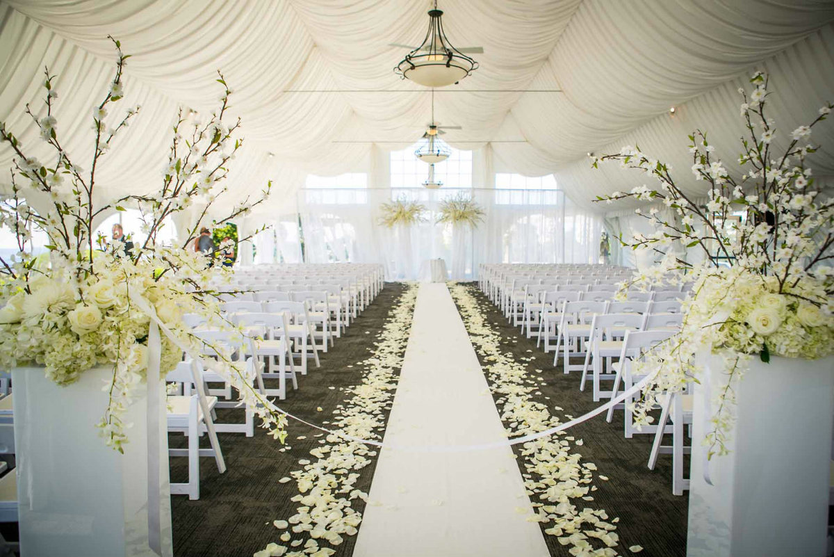 wedding aisle with white rose petals, cherry blossom arrangements, and large arch