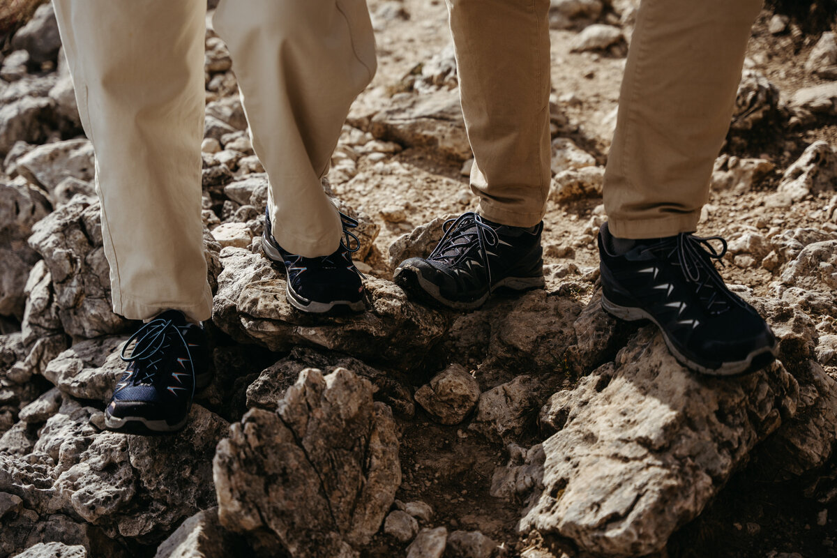 Close-up of hiking boots stepping on alpine rocks