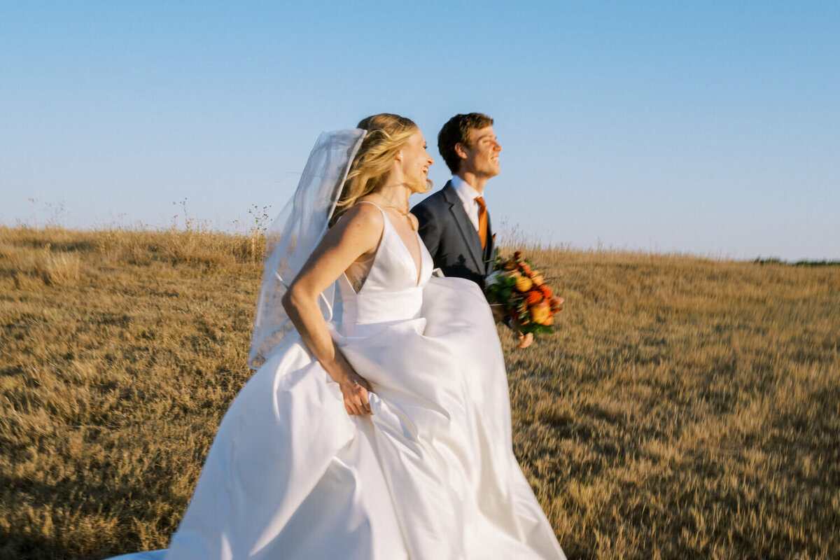 bride-and-groom-running-through-field