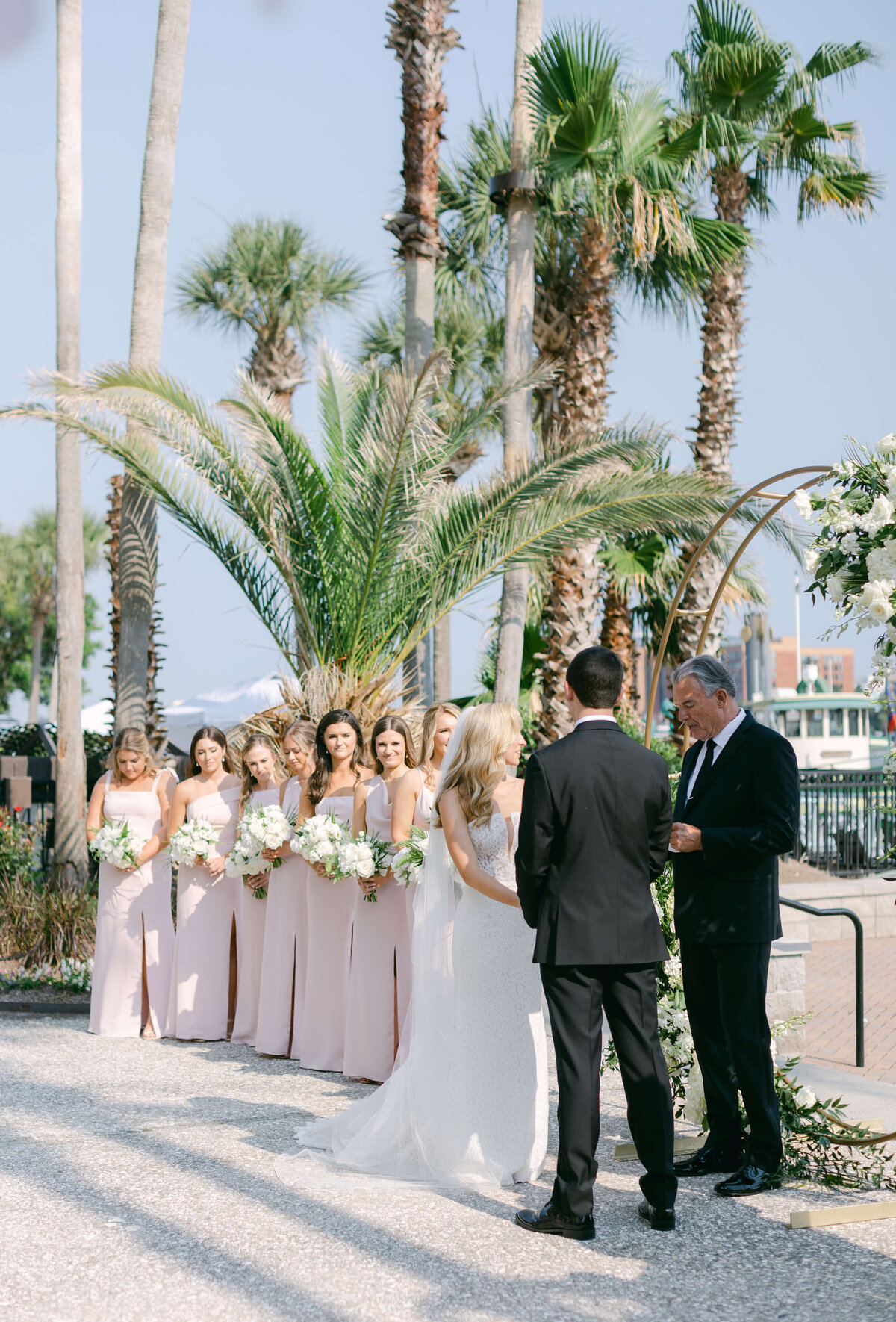 A bride stands before her groom backed by her bridesmaids.