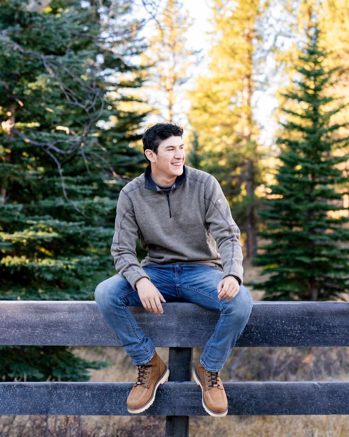 boy smiling and sitting on fence