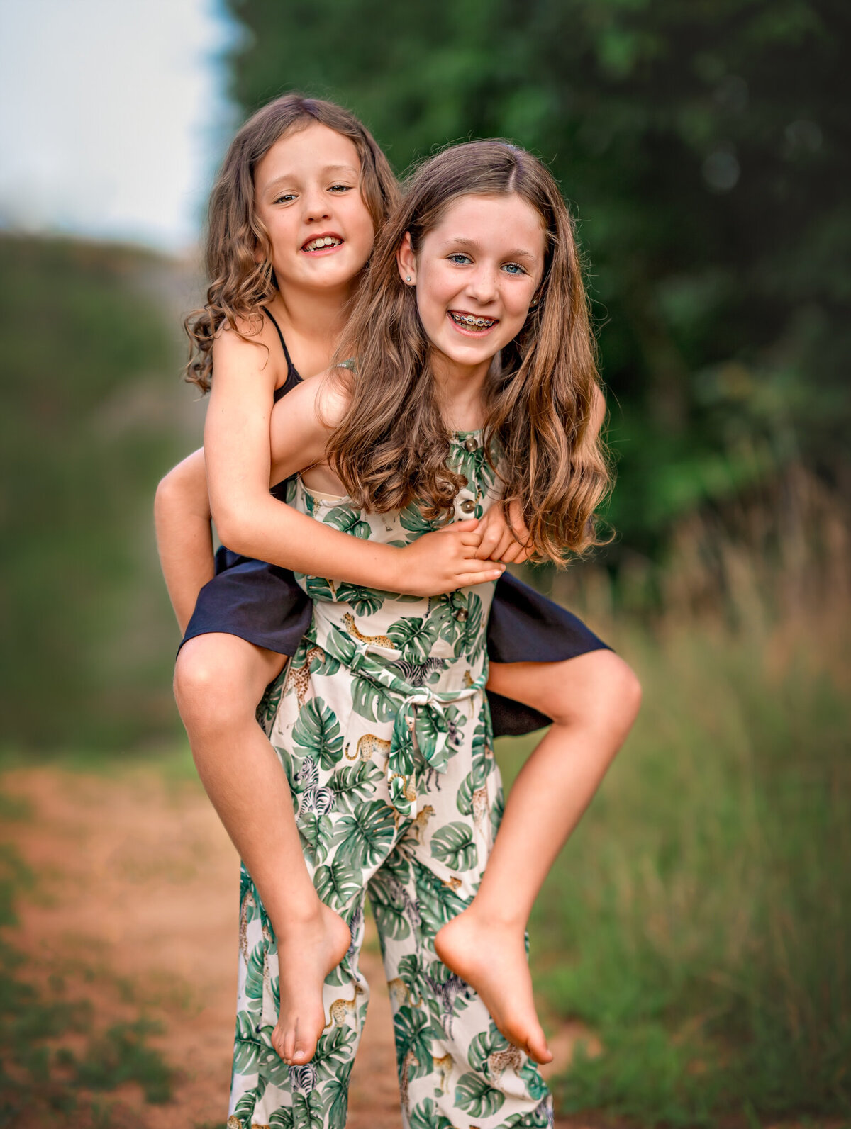 An older sister is carrying her younger sibling on her back.