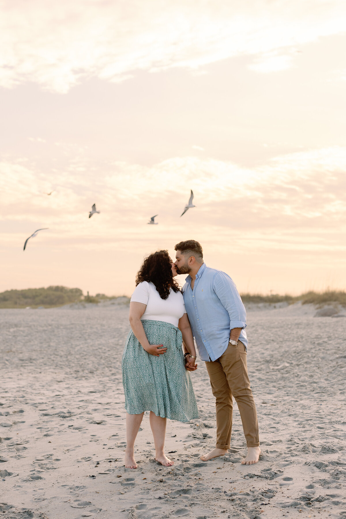 Husband kissing pregnant wife on Wilmington beach, intimate maternity photography