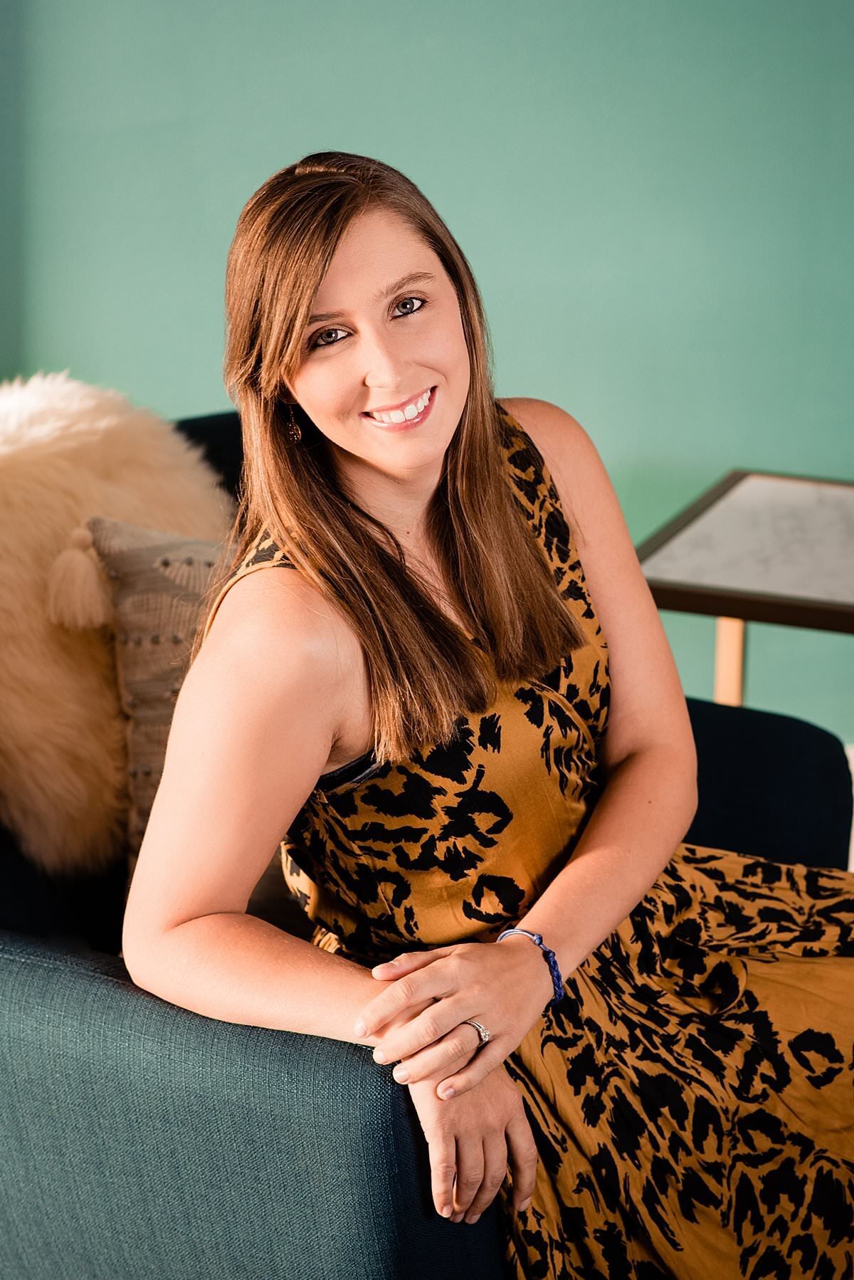 Headshot photo of boss babe smiling at camera sitting on a chair