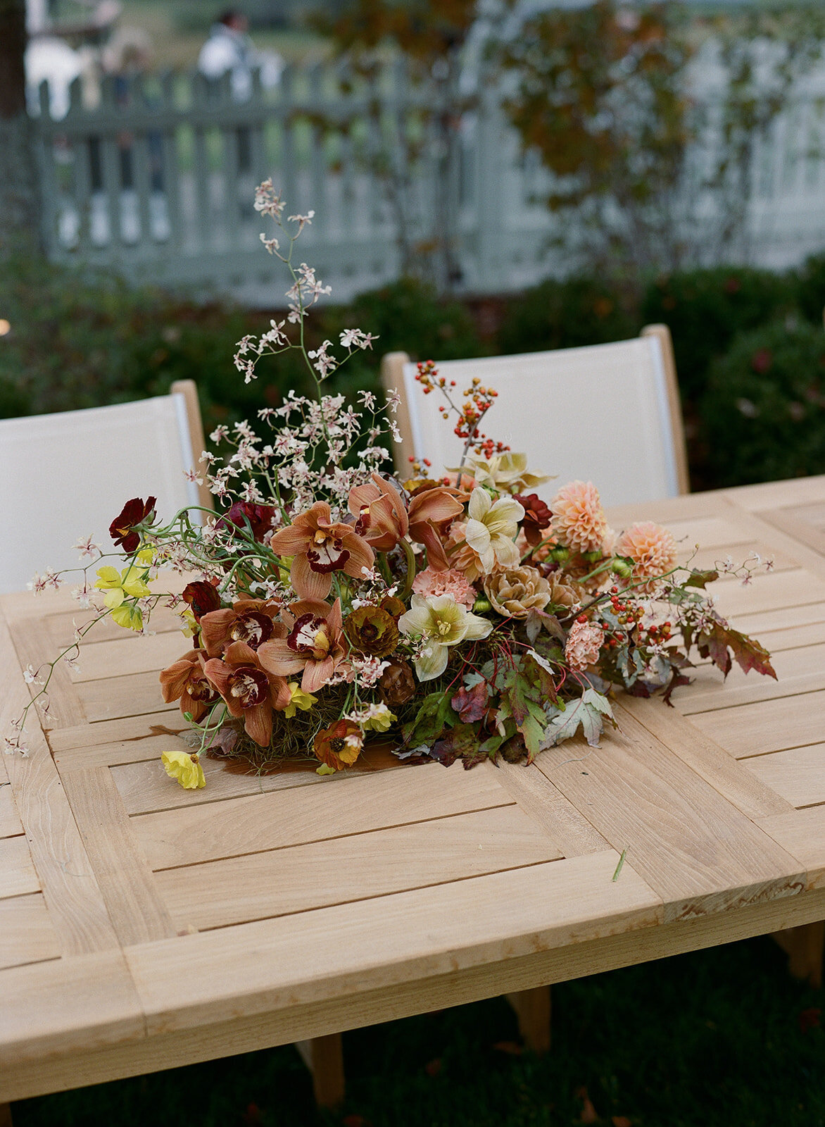 Sculptural ikebana and meadow arrangements decorate the cocktail hour for private estate wedding in Tennessee hills.Clear top tent build out for fall wedding reception in Tennessee hills.  Trailing bar arrangements and floral meadow centerpieces for autumnal wedding reception. Orchids, bittersweet berries, butterfly ranunculus, and tulips are highlighted. Artistic fall color palette in copper, gold, ruby, lavender, and rust. Design by Rosemary & Finch Floral Design in Nashville, TN.