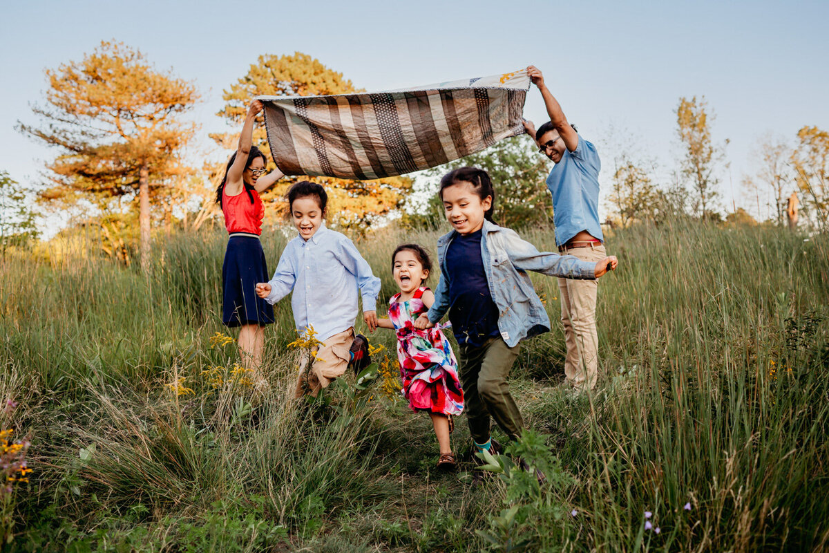 3 siblings running under blanket during toronto family photography session