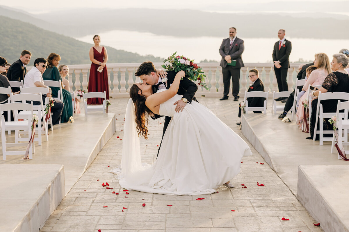 Just-married couple sharing a celebratory dip in the aisle at the end of their wedding ceremony at Stone Haven, a new luxury venue in Section, Alabama.