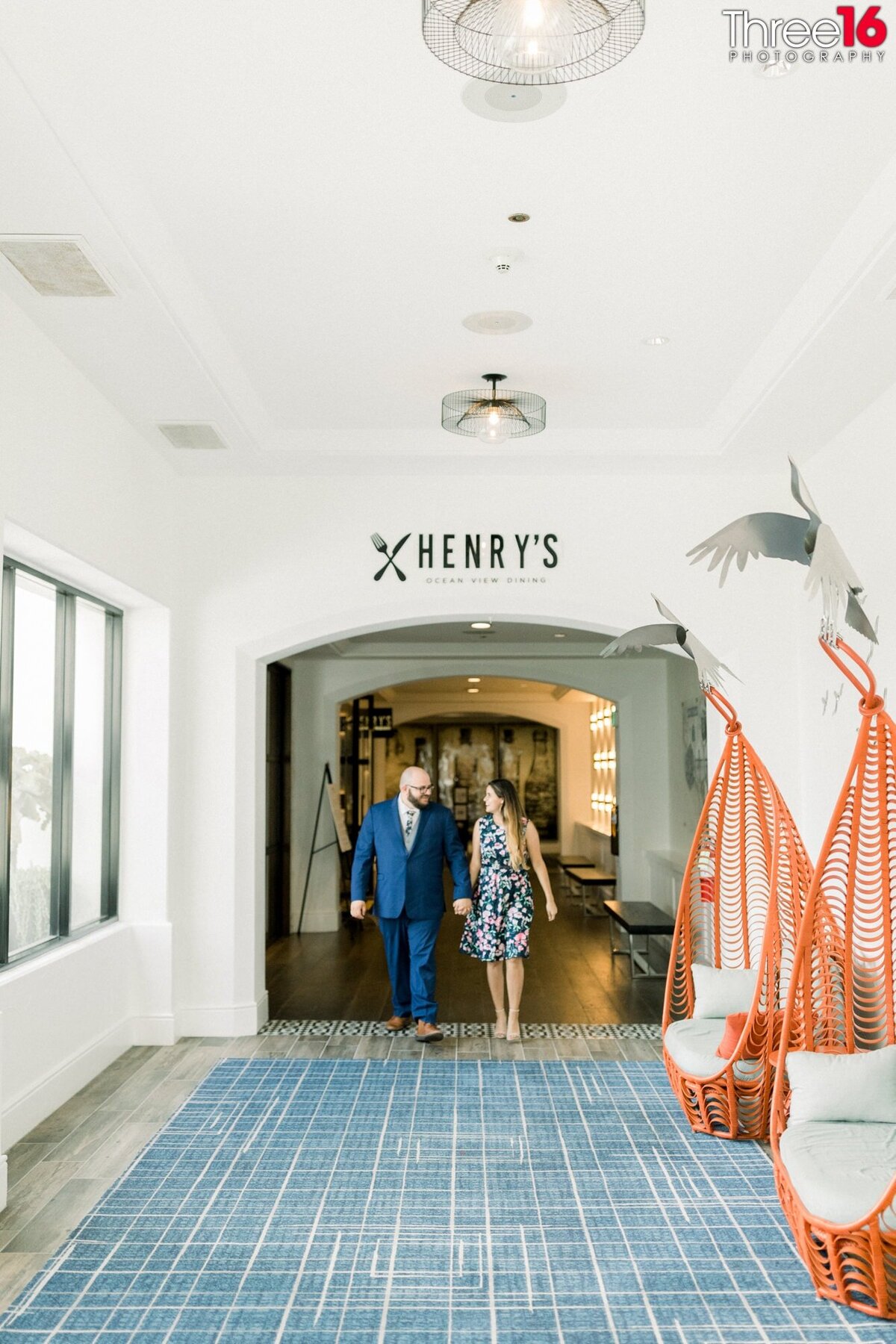 Engaged couple walks through the hallways of Hilton Waterfront Resort while holding hands.