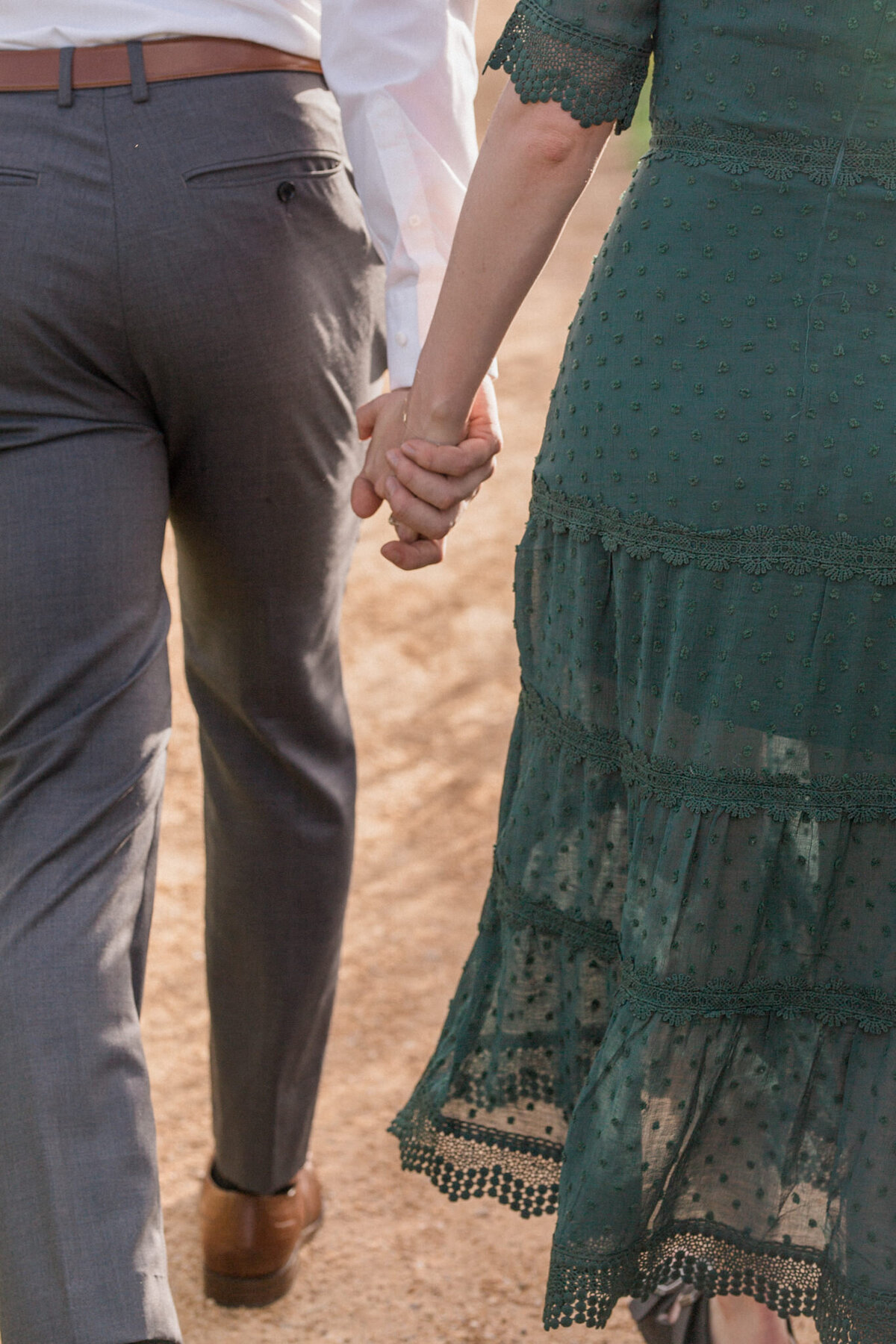 A close up image of a man and woman holding hands as they walk along a path at Boulder's iconic Chautauqua Park