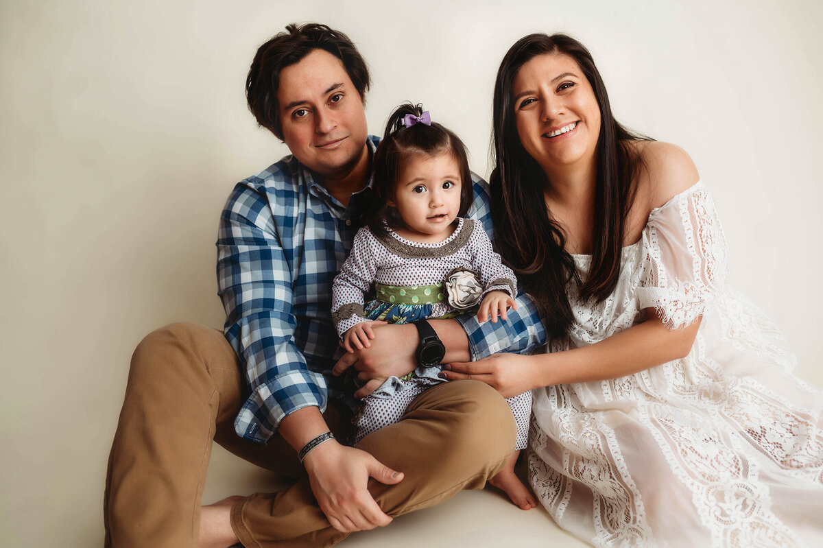 Parents pose for portraits with their daughter during Cake Smash Photoshoot in Asheville, NC.