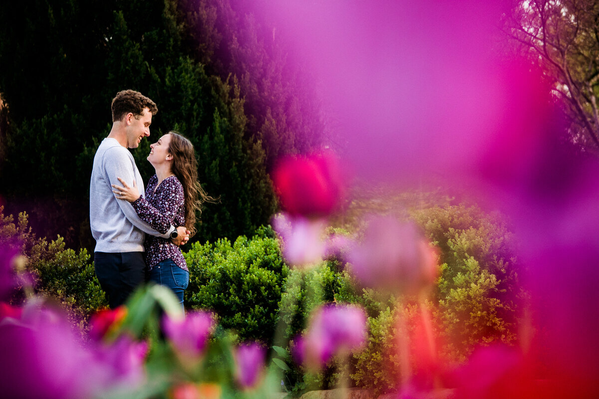 A couple standing in the garden of the National Cathedral surrounded by flowers