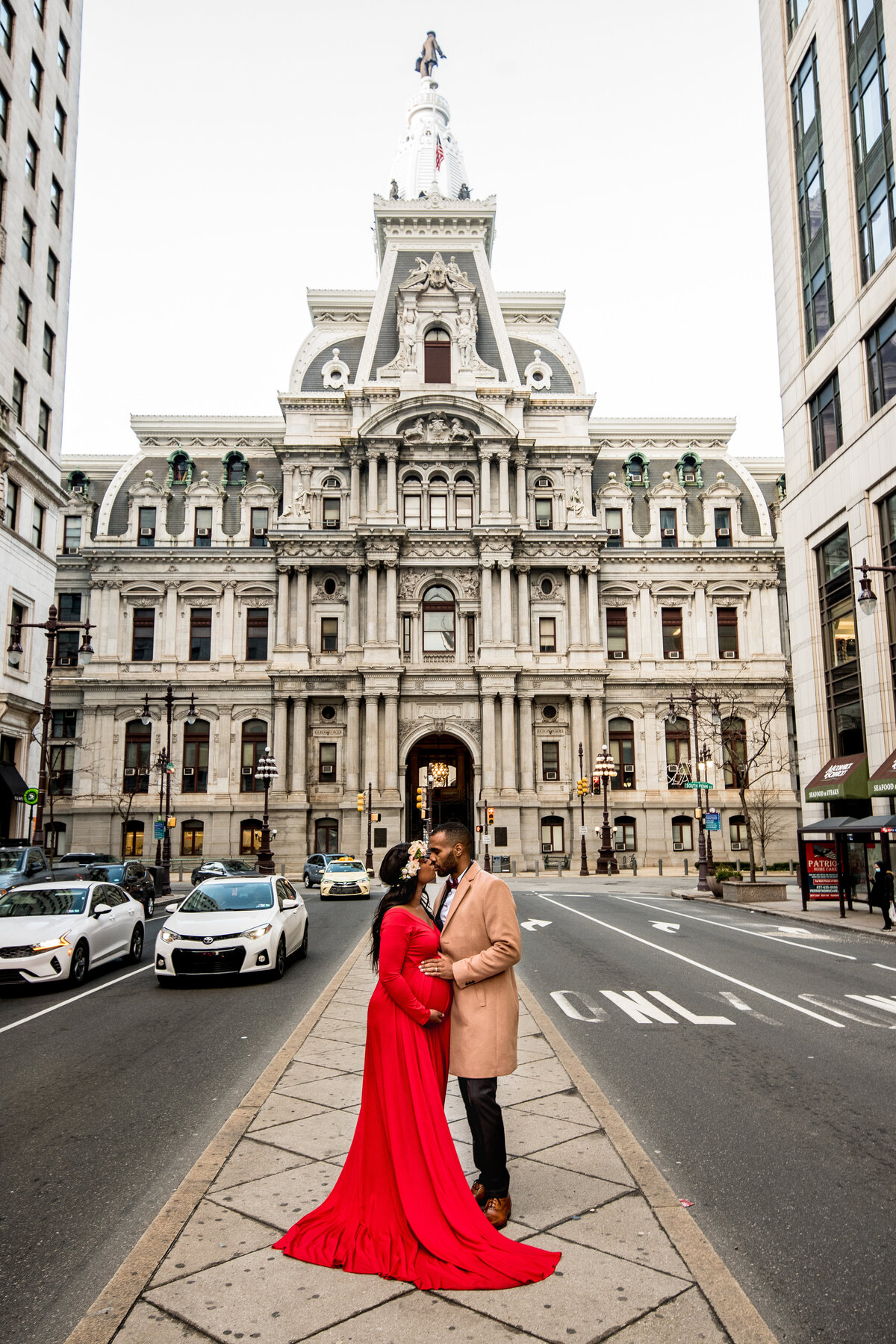 A couple stands in front of an old, ornate building for their maternity photos