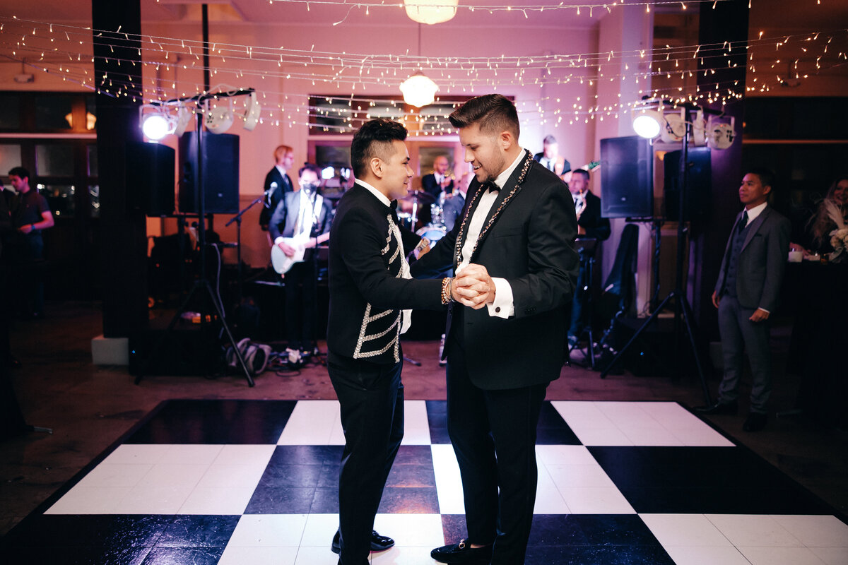 Groom's share a slow dance on a checkered dance floor on their wedding night.