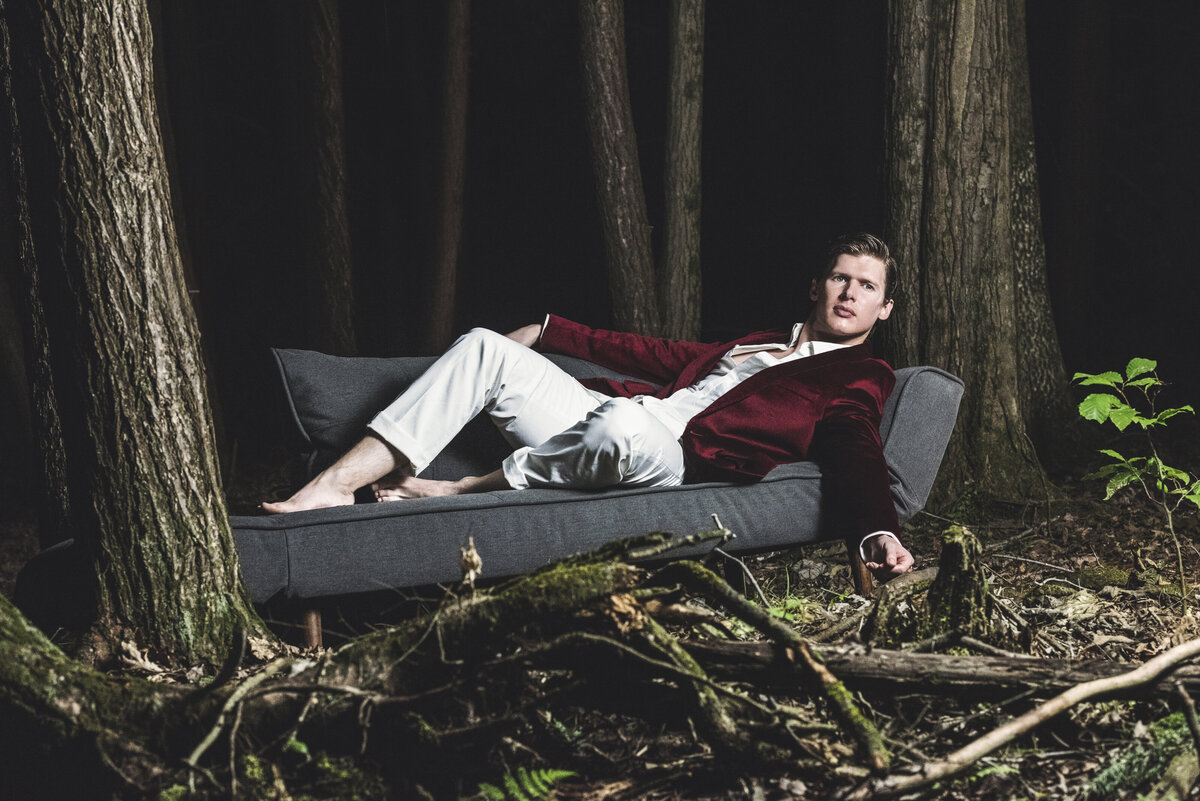 A person laying on a couch in a suit in the woods