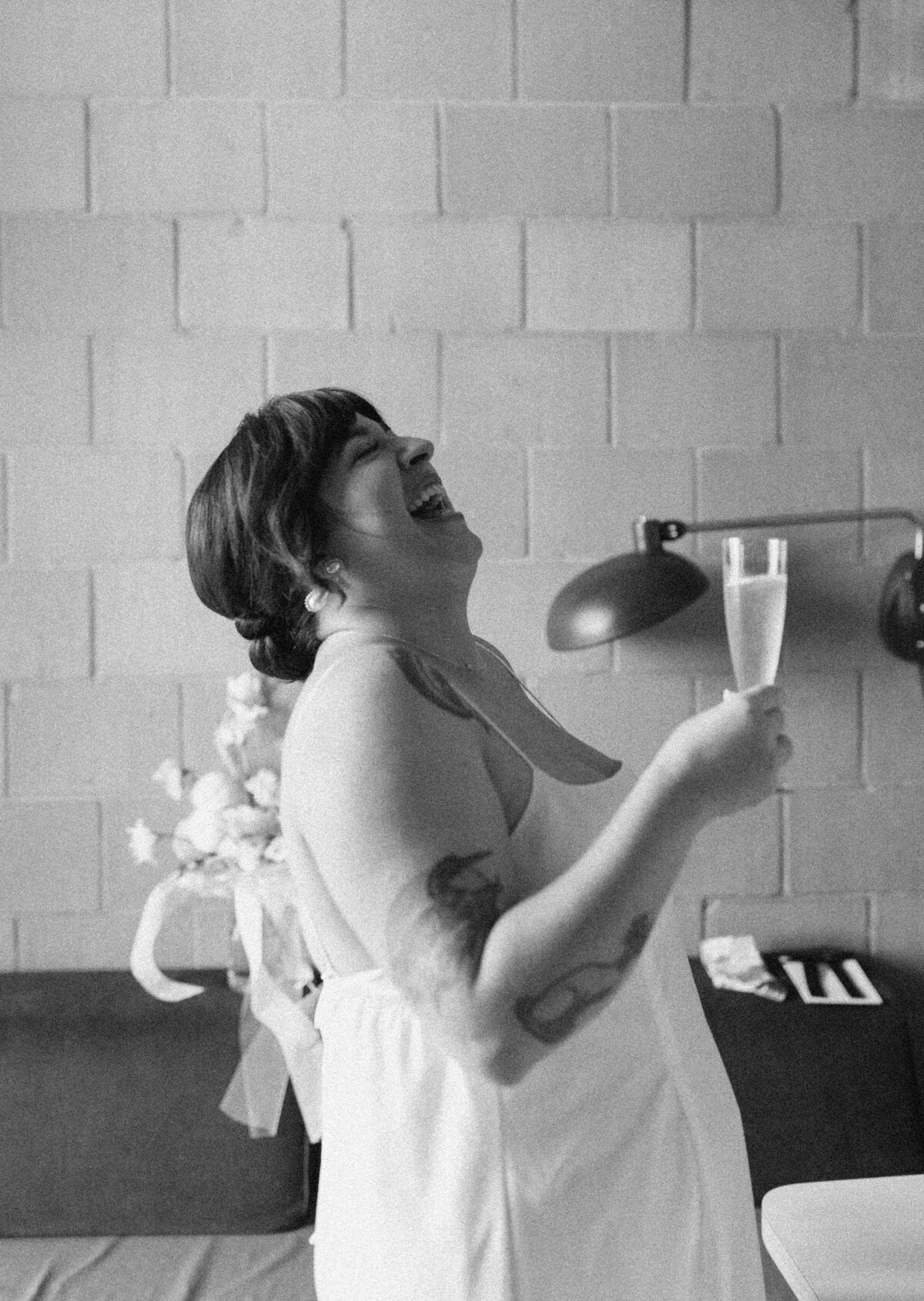 Bride laughing, holding a champagne flute at Carpenter Hotel Austin