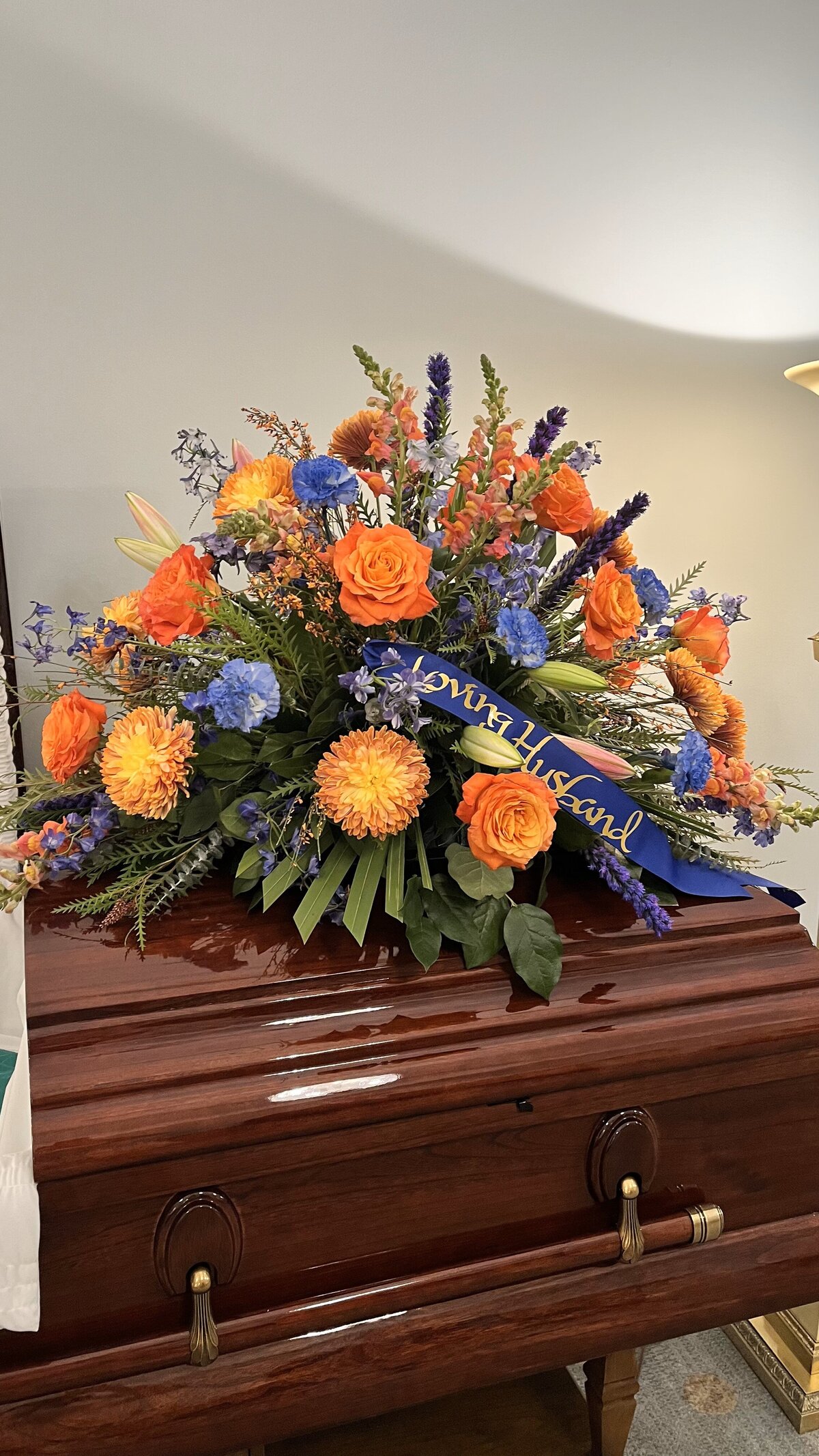 bright orange and blue funeral casket flowers at White Pine Funeral Flowers