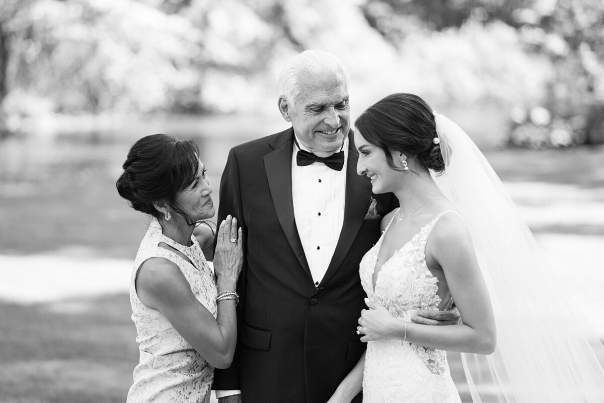 mother and father of the bride embrace while talking to the bride before her ceremony