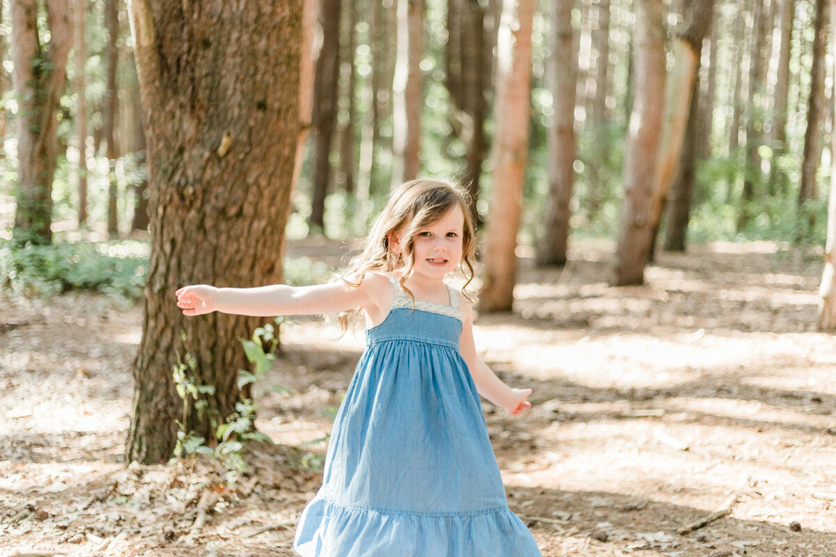 little girl spinning in the woods