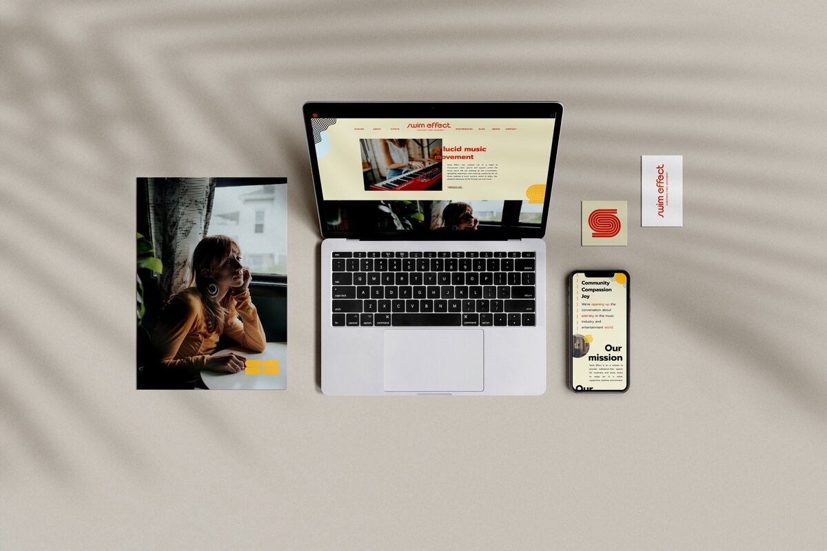 Image of a laptop, smartphone, business card, and brochure displaying matching designs with a red and yellow color scheme on a light surface—perfectly showcasing seamless brand strategy consulting from an expert brand designer.