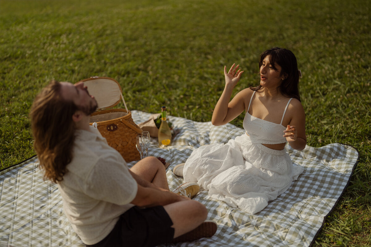 A candid moment of the woman sitting and smiling during a playful picnic session near White Rock Lake in Dallas.