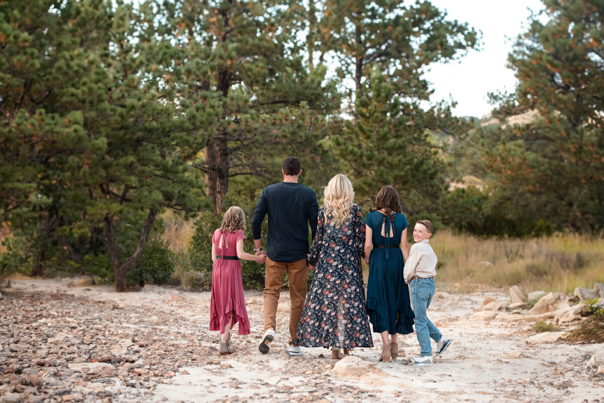 A family walks down a trail holding hands while the youngest boy looks over his shoulder