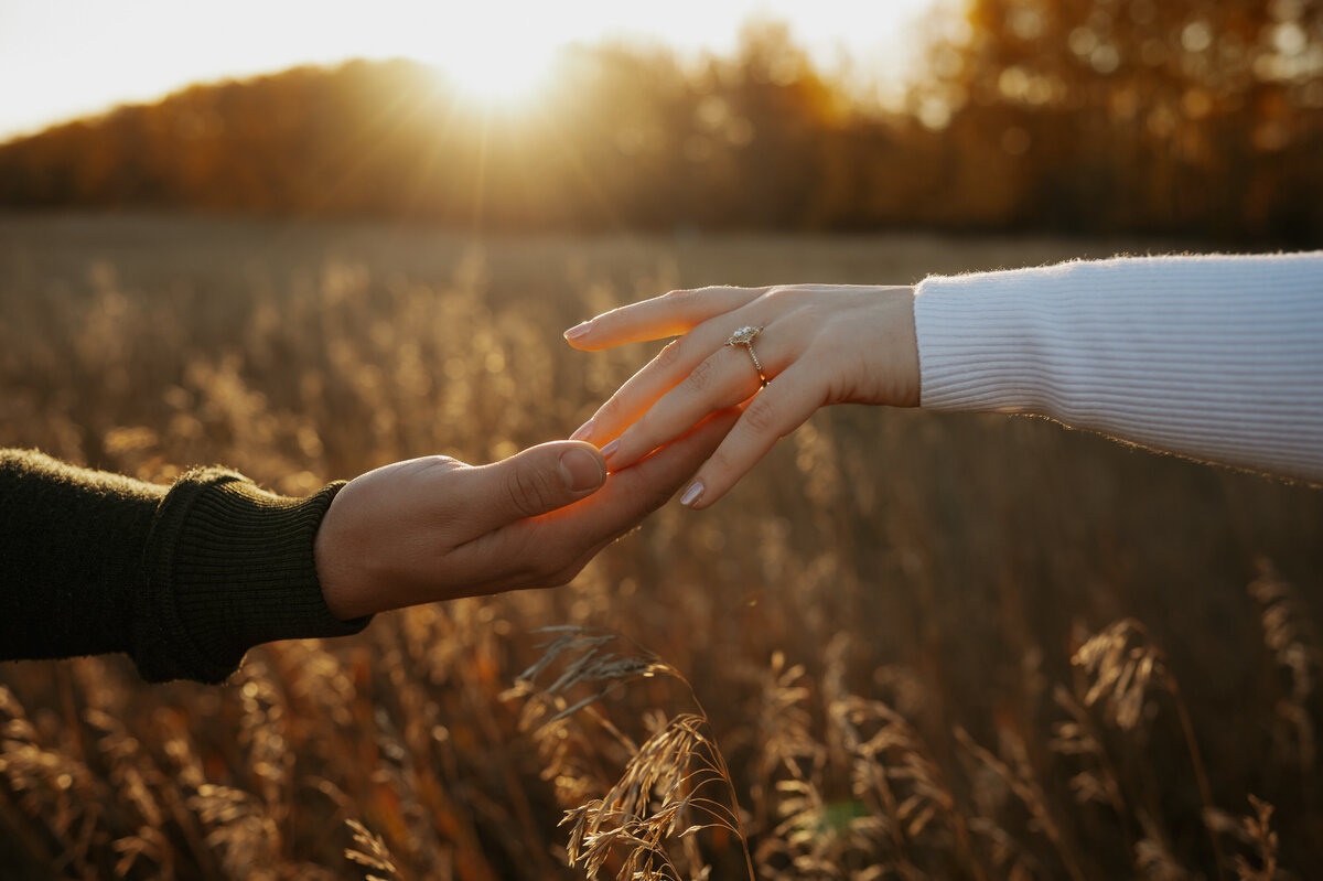 Sunset photgraph of couples hands capturing beautiful engagement ring