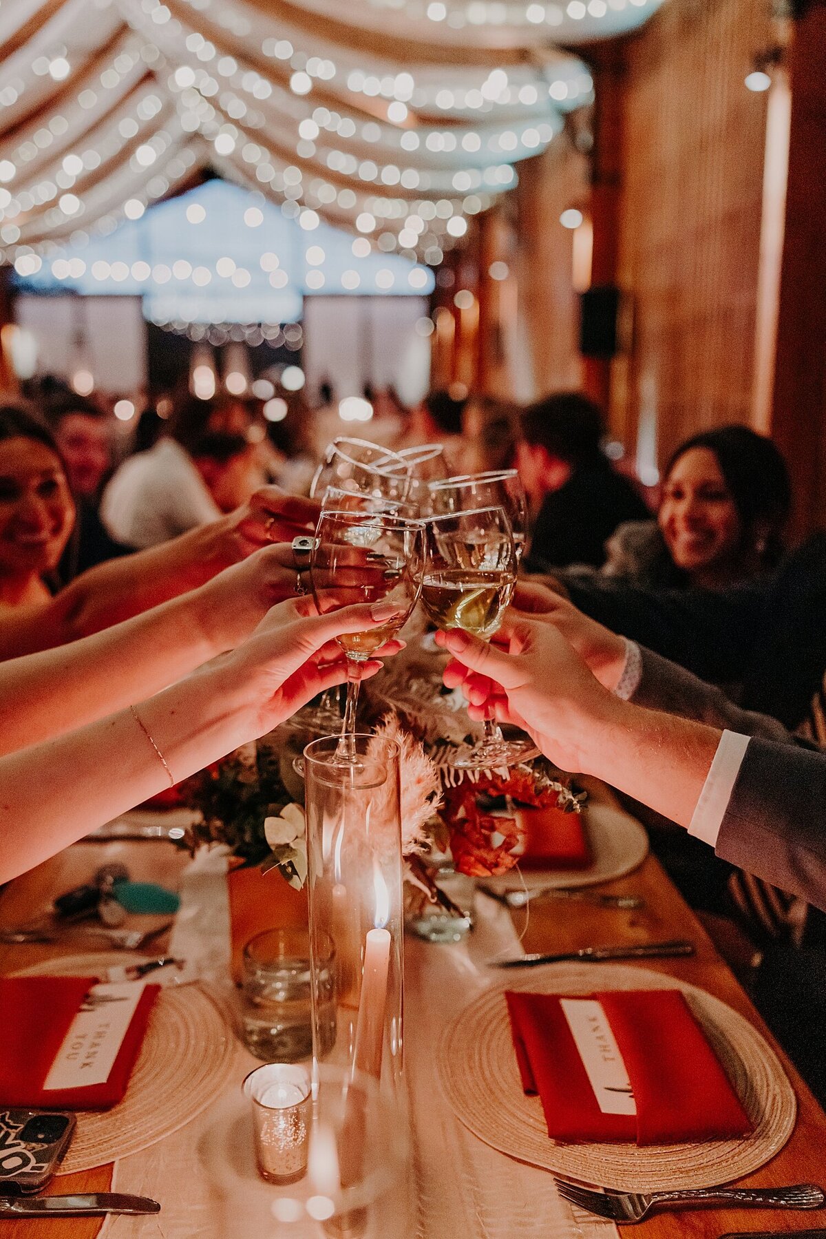Wedding guests clink champagne glasses at candlelit dinner