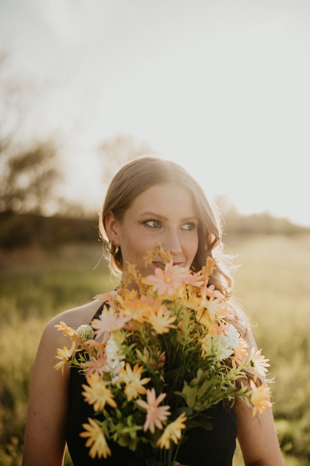 senior holding flowers at sunset in field, senior portrait photography, , Emily wheeler photography