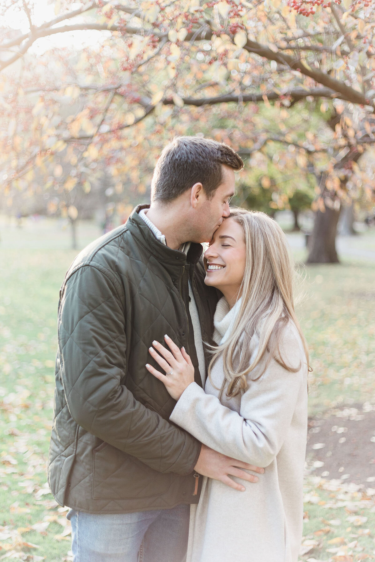Man kisses his fiancee's forehead in the Boston Public Garden