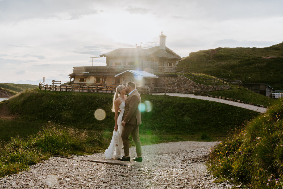 Sunburst behind couple walking on trail at Passo Giau
