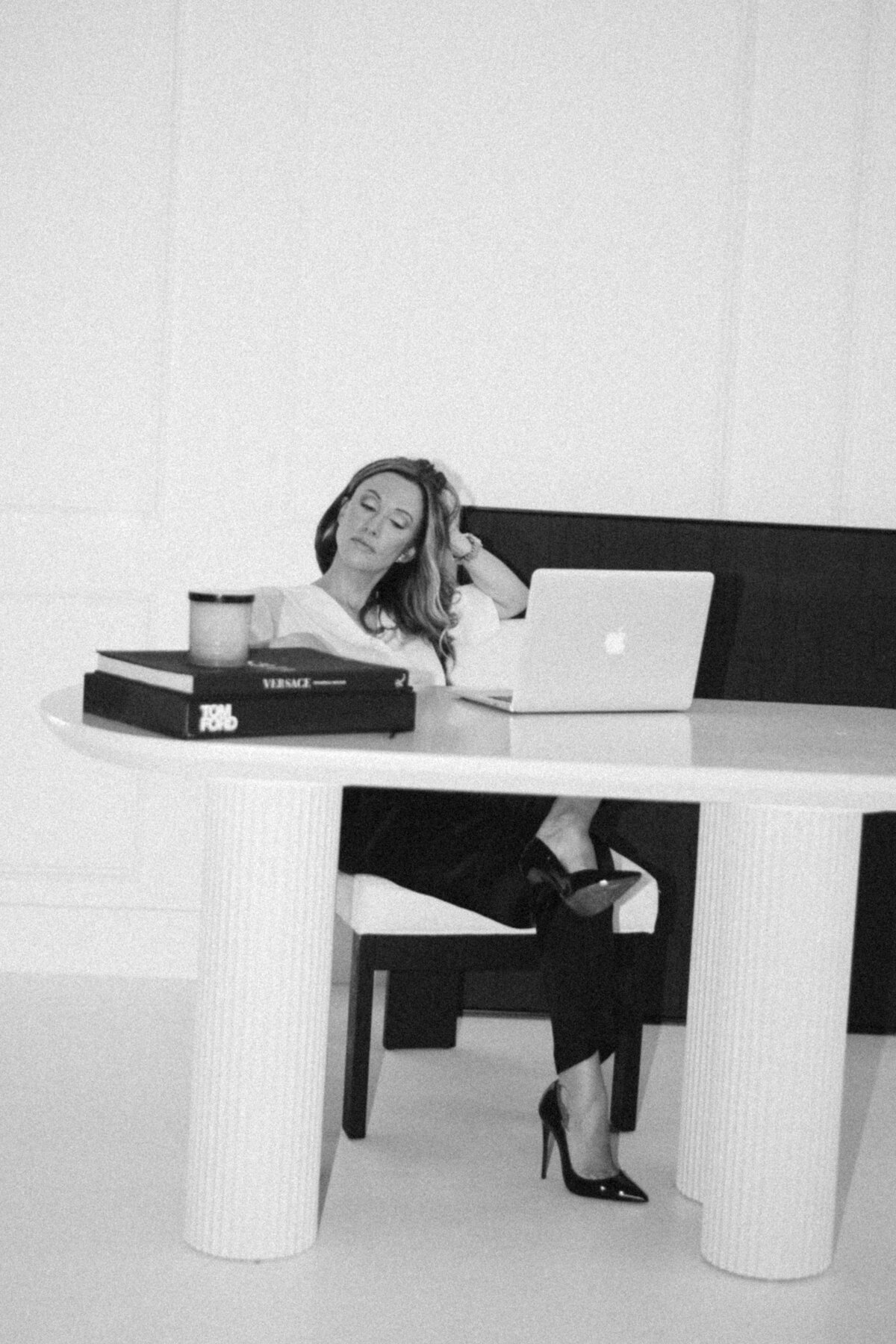 Black and white branding headshot of a woman at desk