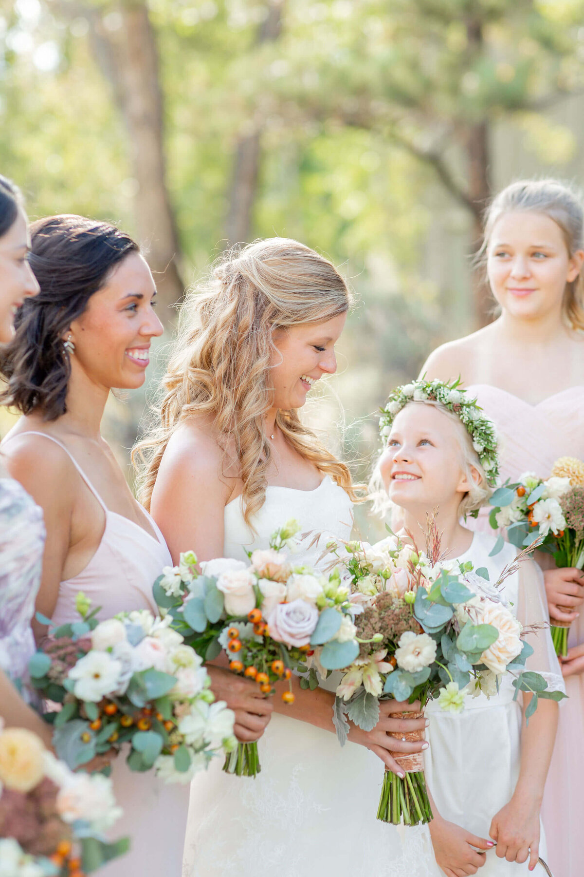 flower girl smiles and looks up at bride holding bridal bouquet