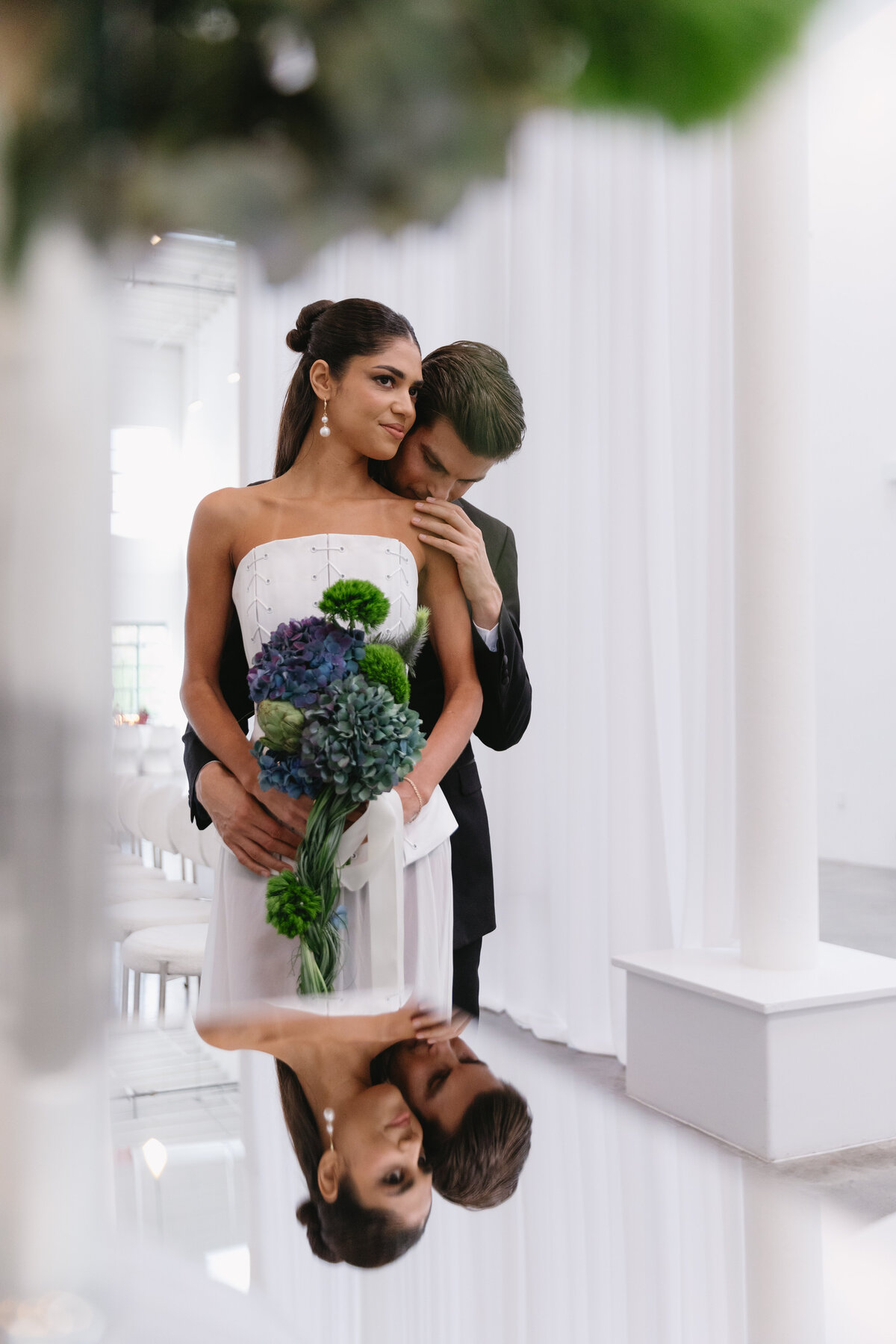 Bride touching groom’s face while posing during an editorial NYC wedding photoshoot with clean white drapery.