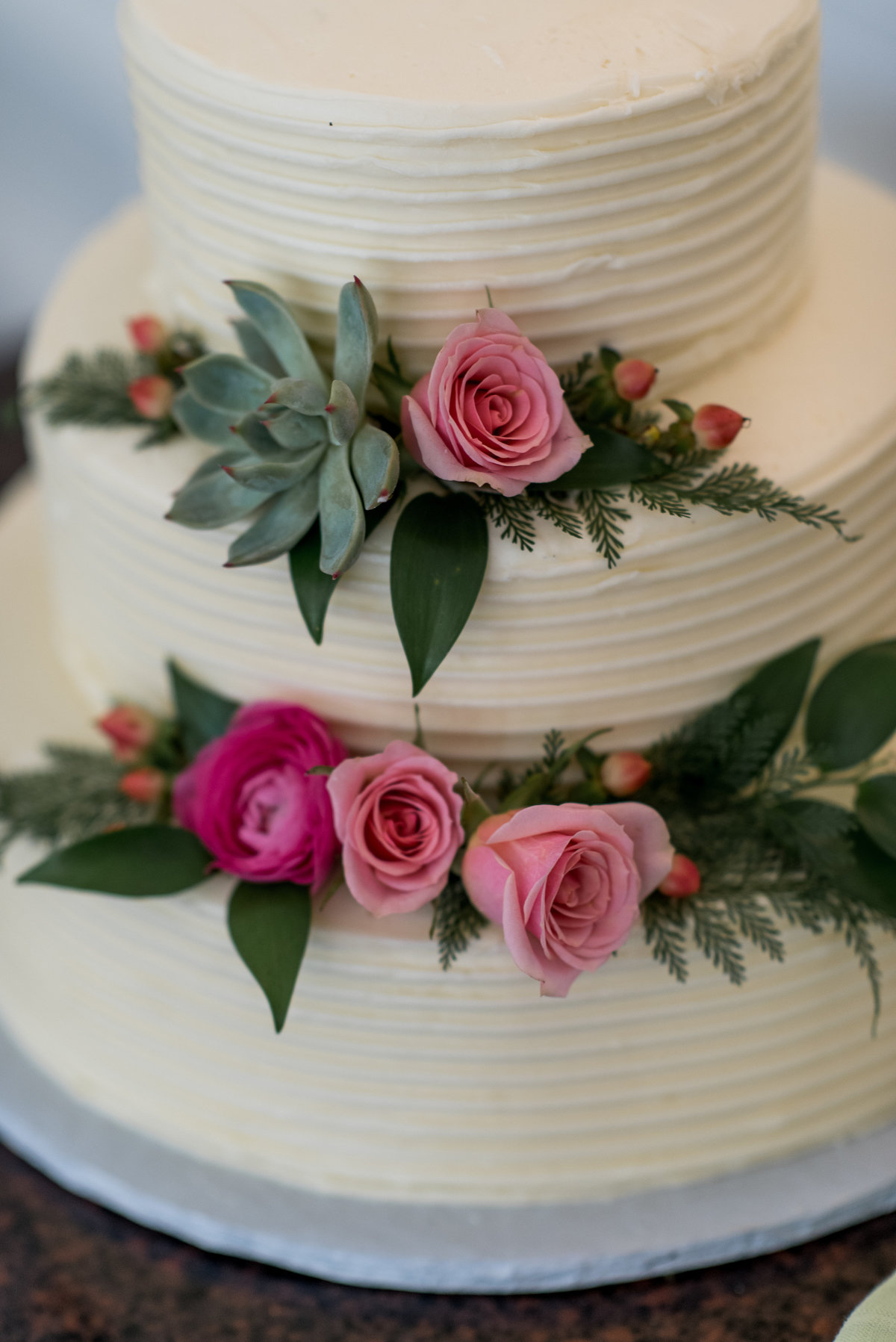 Wedding cake with  floral décor including pink spray roses and succulent