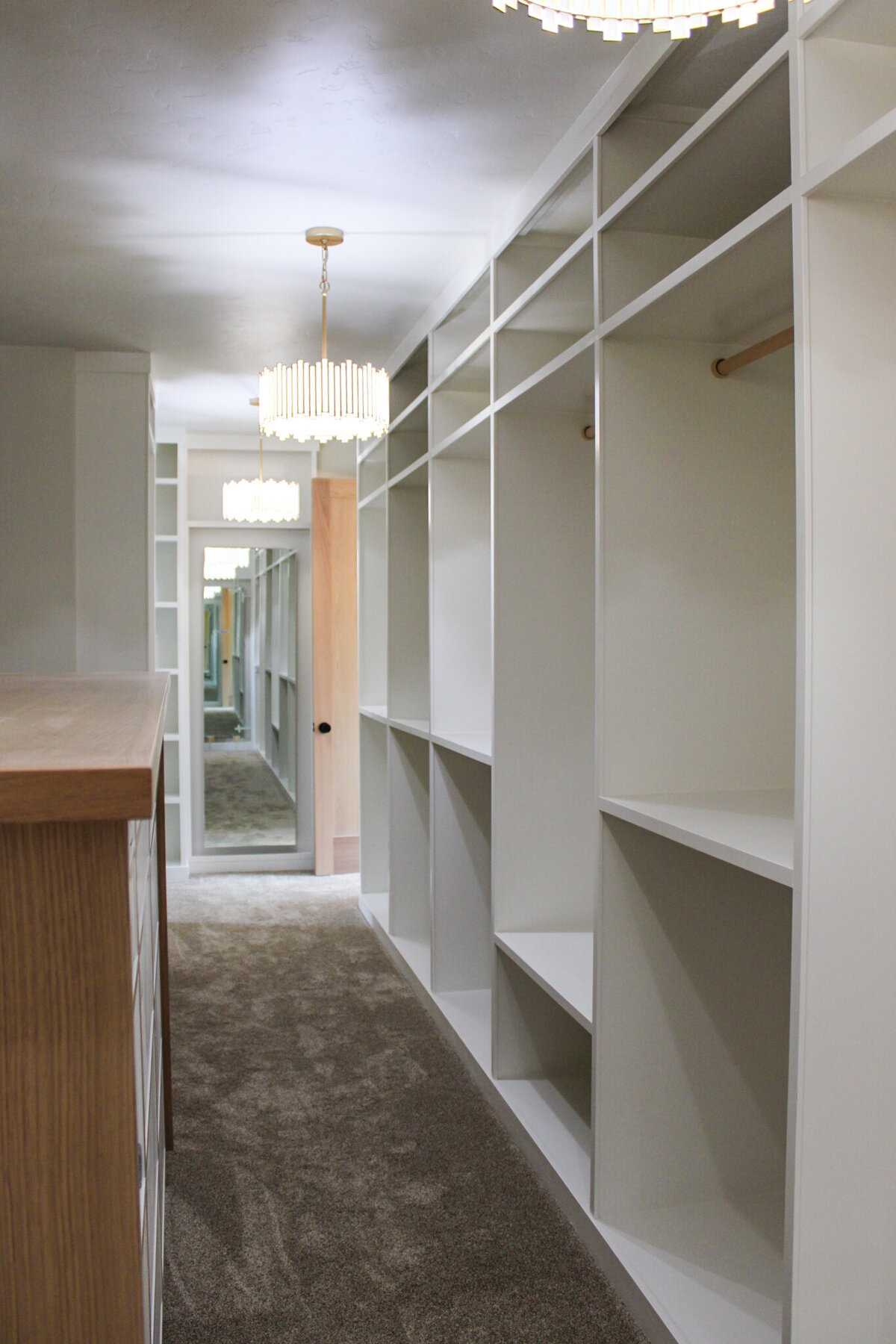 walk in closet with white shelving and brown carpet