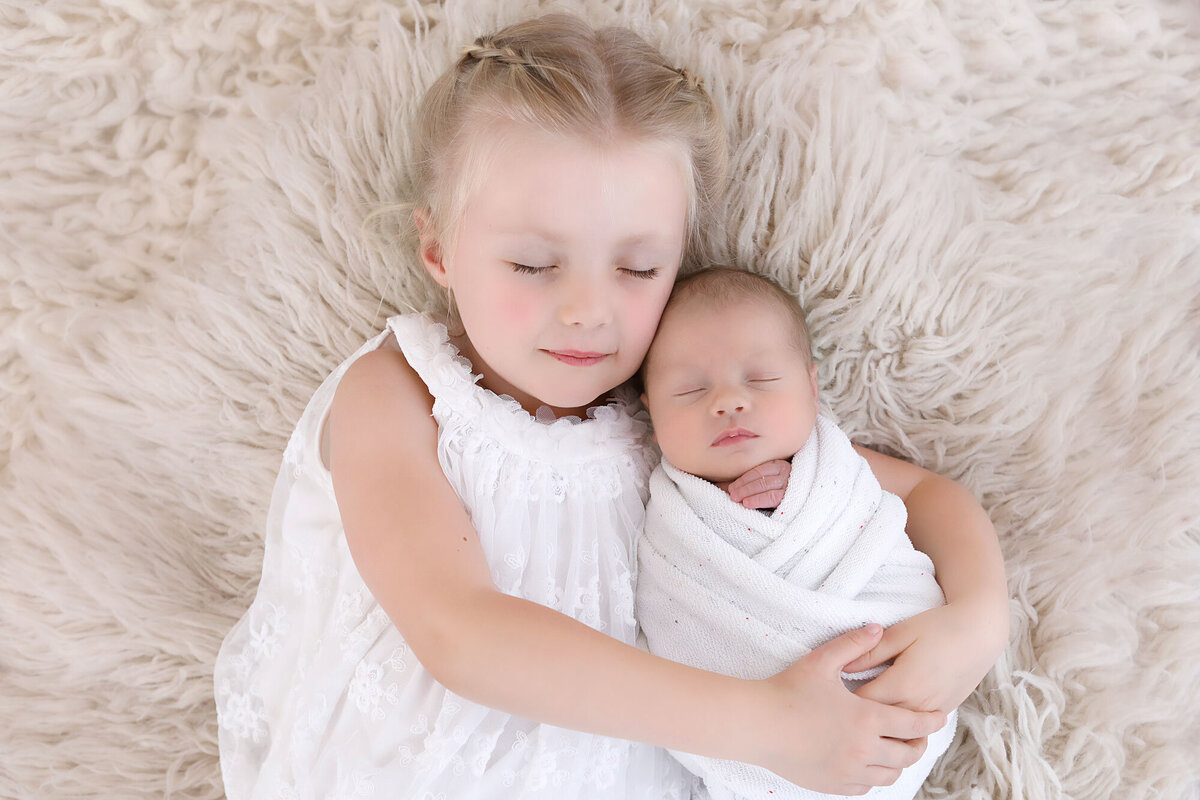 Big-sister-holding-her-newborn-baby-sister-in-her-arms