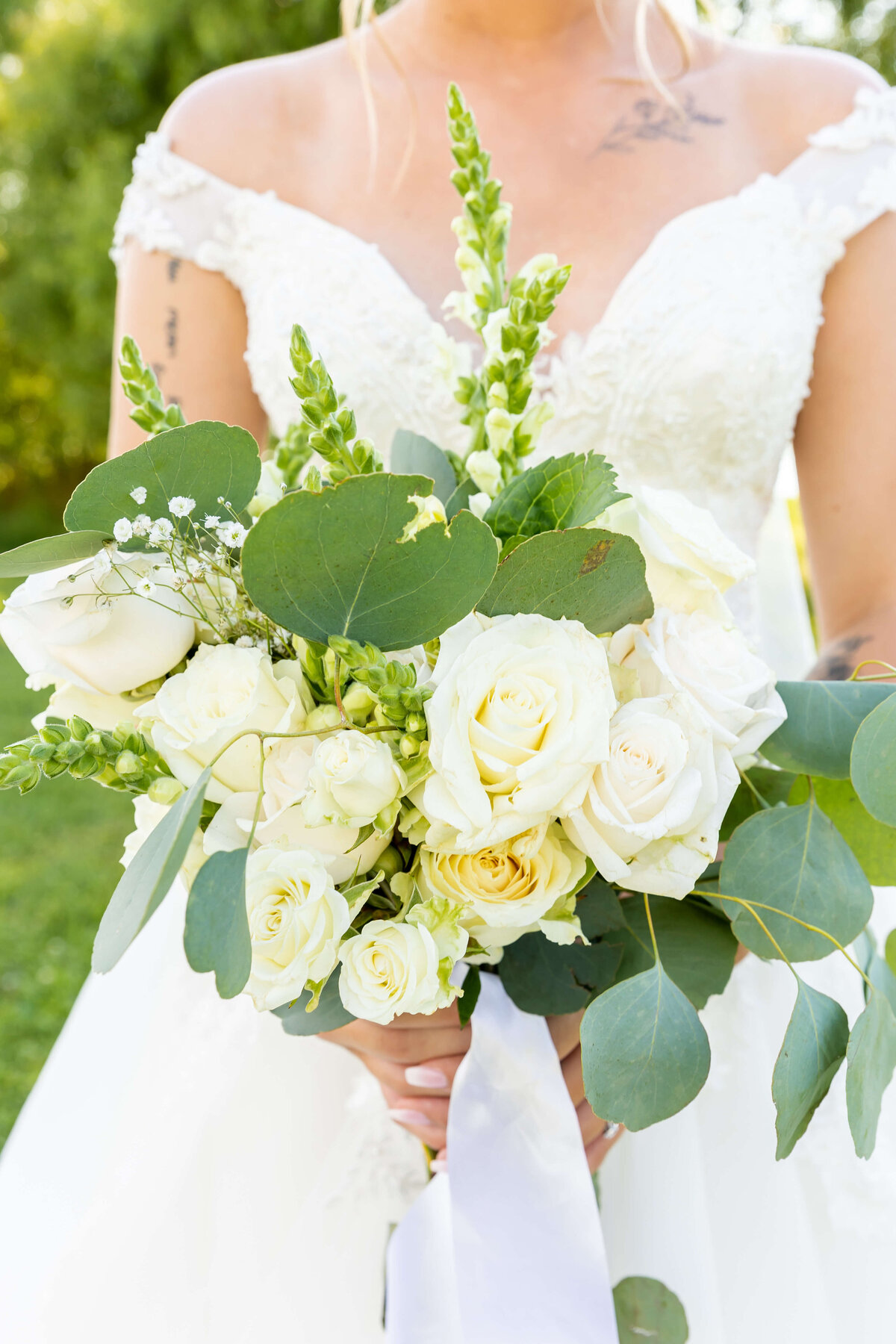 Bride holding bouquet of white florals and greenery