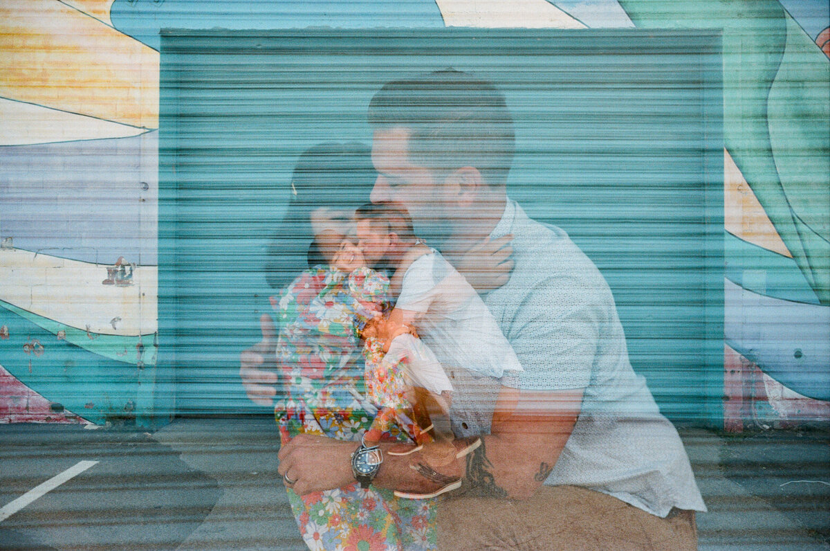 photo taken through window of mom with two kids painting on the glass