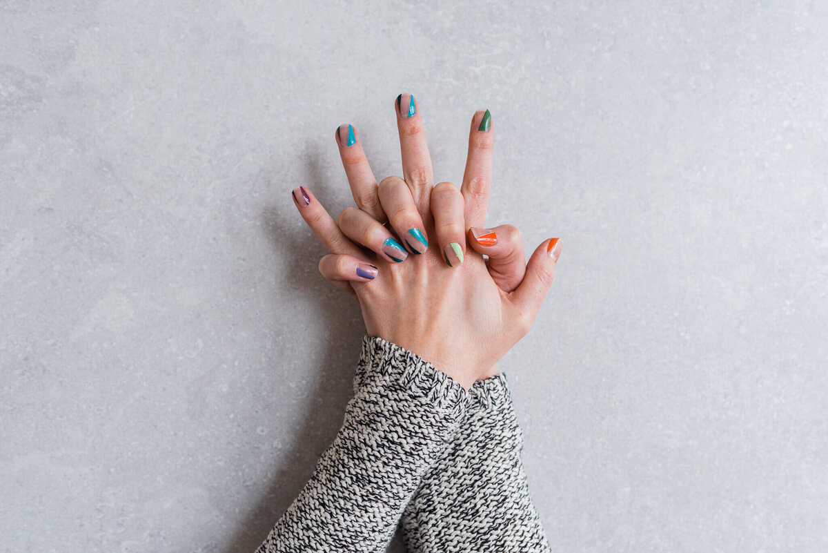 A hand model showing off rainbow stick-on nails