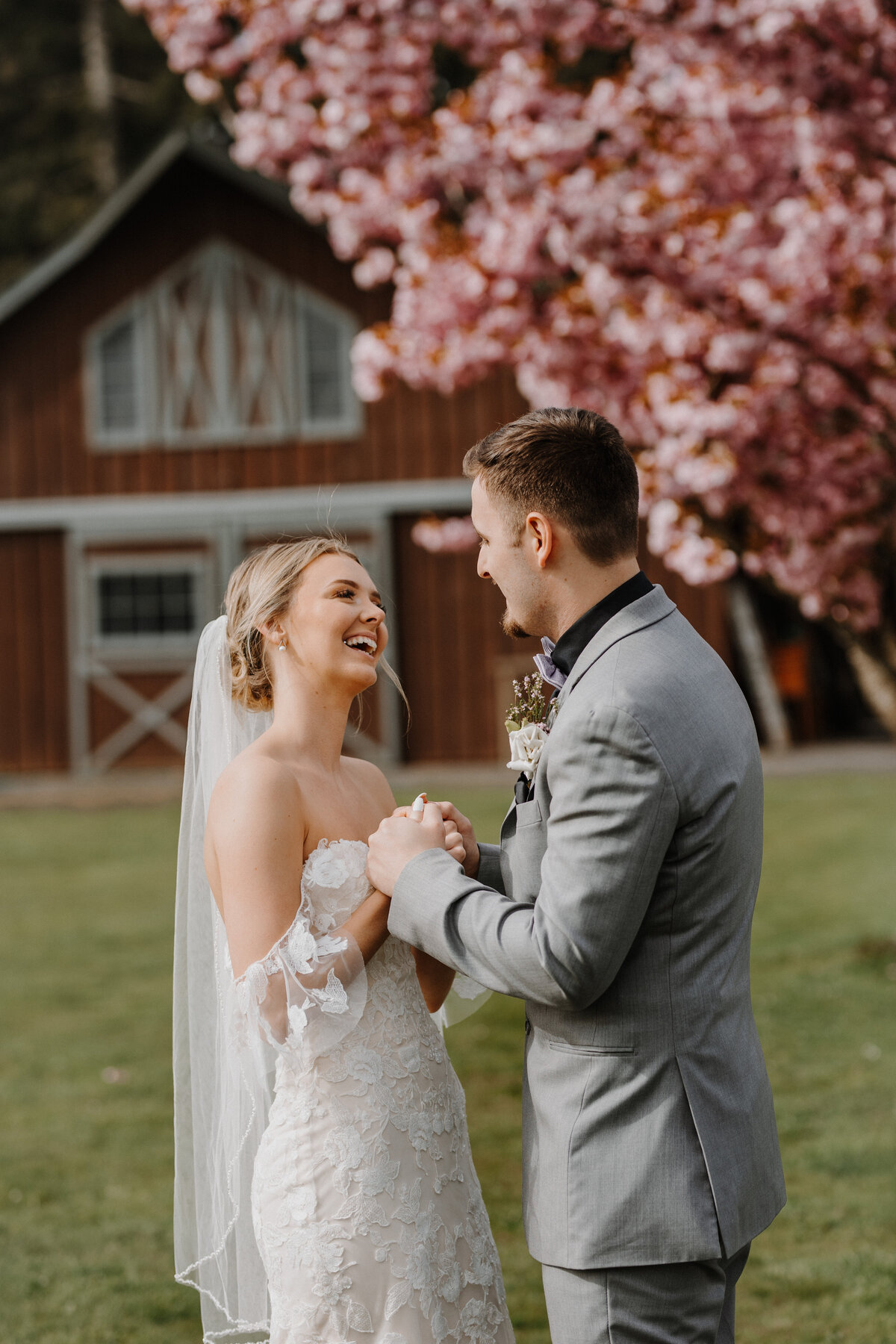 Bride laughing at groom in front of red barn