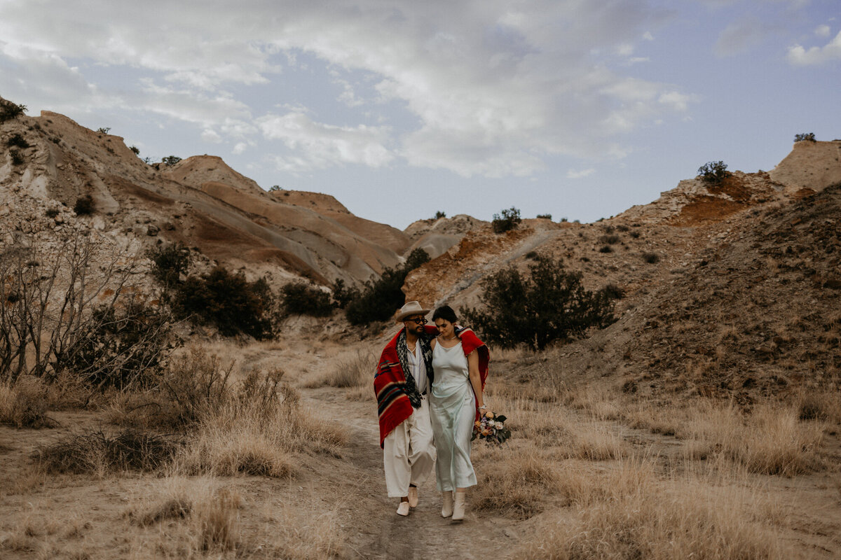 an interracial bride and groom walking together in the desert