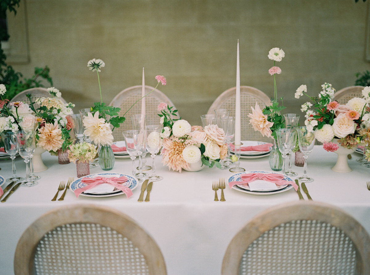 luxury wedding table setup with ivory tall candles and small table floral arrangements with light coloured roses and dahlias