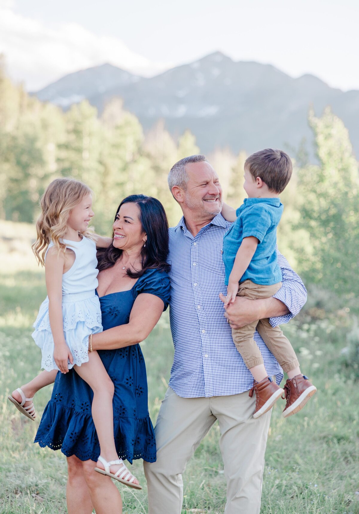 Grandparents stand smiling with their grandkids sitting on their hips