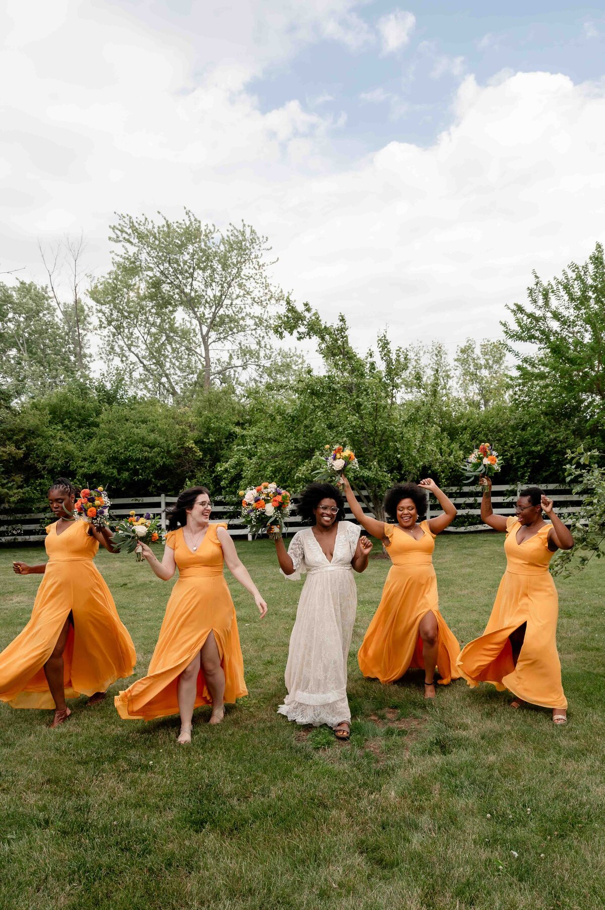 Bridesmaids wearing yellow dresses walk on field