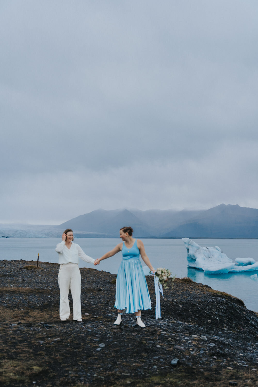 Women walk looking at each other while holding hands 