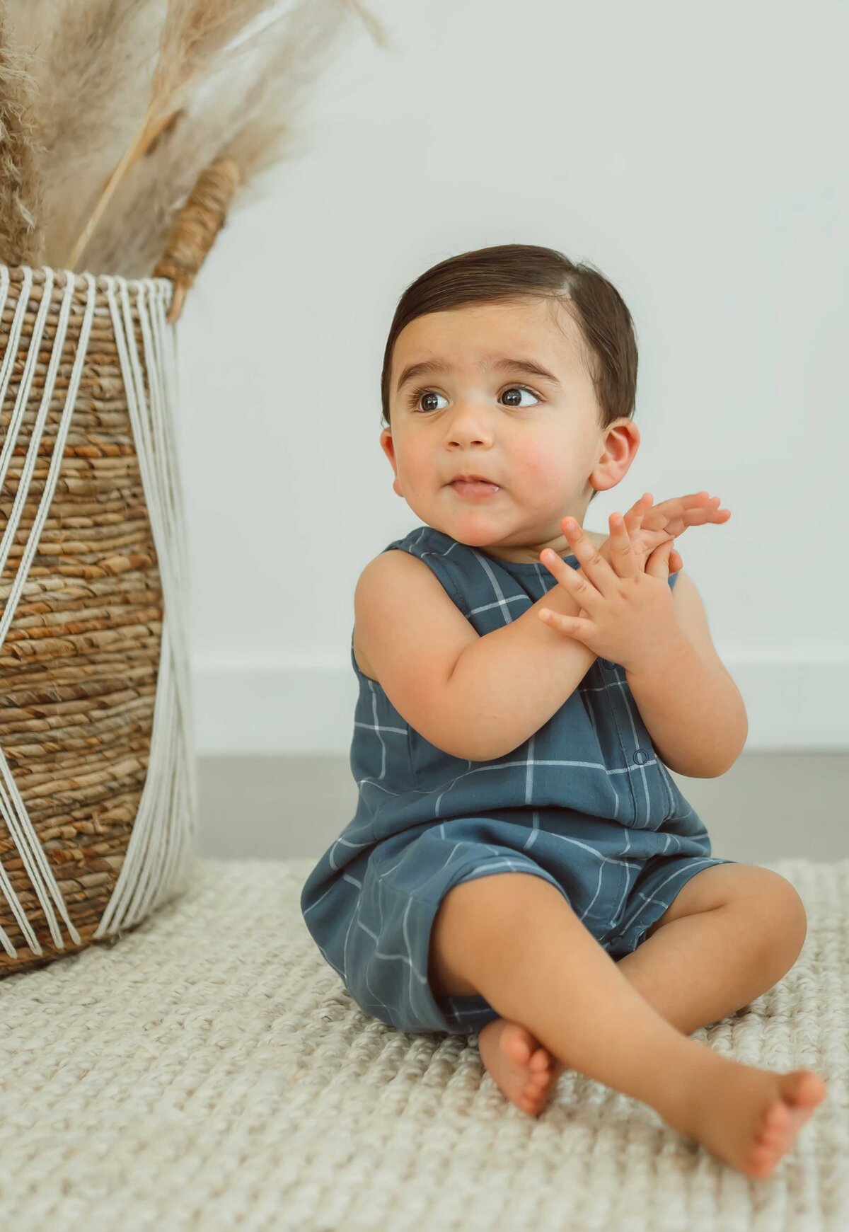 boy sitting on the floor and wearing a blue checkered overall