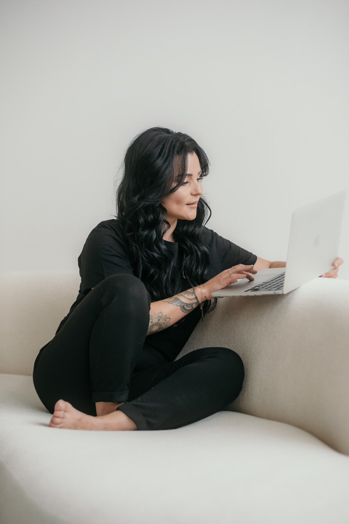 Woman sits on a sofa, working on her laptop