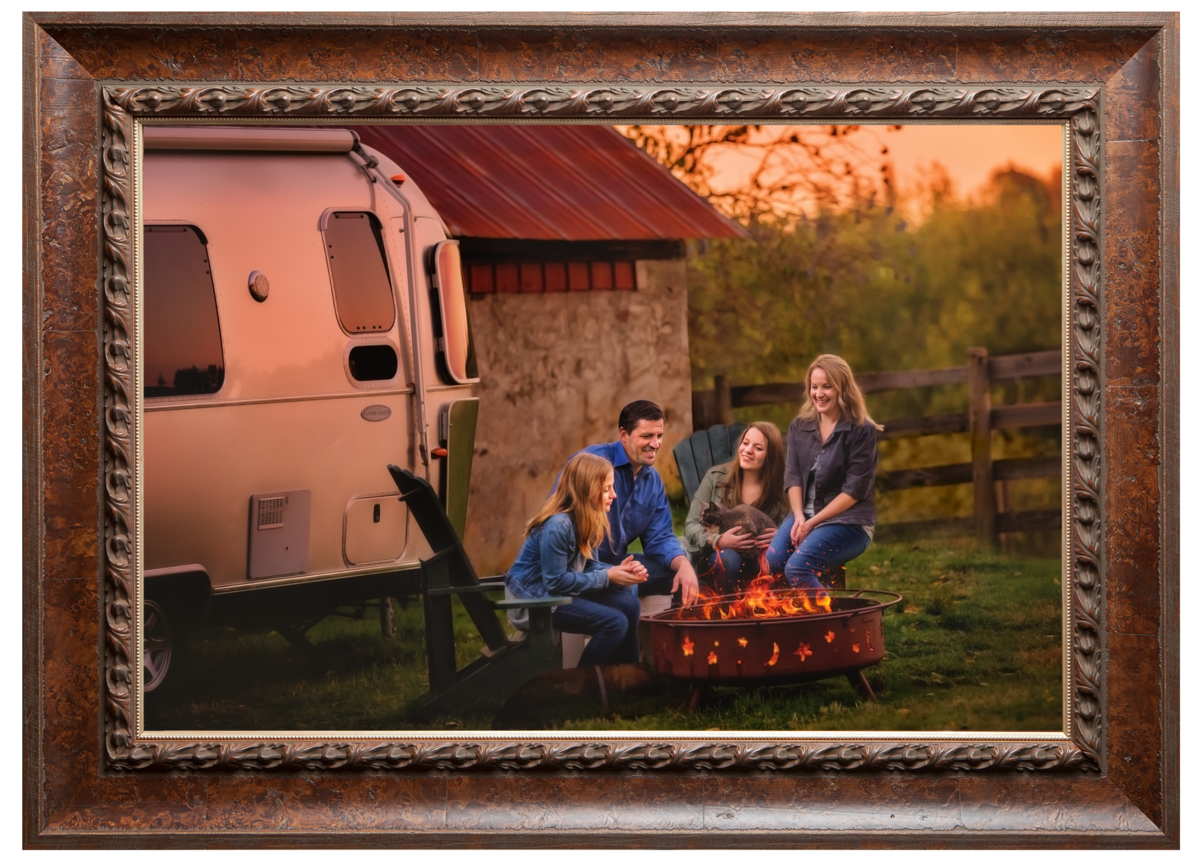 A family of four by a campfire next to an airstream camper on a beautiful summer night in Colorado.
